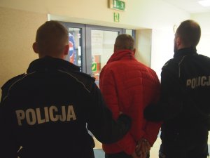 Policjanci z prewencji wyprowadzają skazanego do konwoju