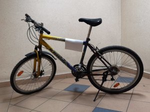 Na zdjęciu widać rower typu górskiego w kolorze żółto-niebieskim.