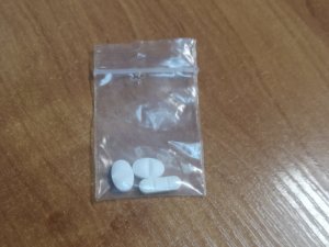 Na zdjęciu widać foliowy woreczek z zawartością trzech tabletek.