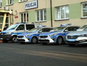 Zdjęcie przedstawia radiowozy ustawione w szeregu na dziedzińcu przed Komendą Powiatową Policji w Otwocku.