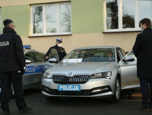 Na zdjęciu jest otwarty pojazd marki Skoda Superb koloru szarego. Obok pojazdu stoi Komendant Powiatowy Policji i Prezydent Miasta Otwocka. W pojeździe na miejscu kierowcy siedzi Starosta Powiatowy Policji w Otwocku.