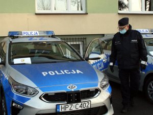 Na zdjęciu jest Komendant Powiatowy Policji w Otwocku, który ogląda oznakowany pojazd marki Kia Ceed.