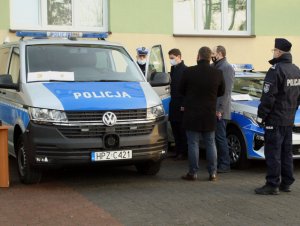 Na zdjęciu jest oznakowany radiowóz marki Volkswagen. Obok pojazdu stoi Komendant Powiatowy Policji w Otwocku, Starosta Powiatu Otwockiego oraz Prezydent Miasta Otwocka, którzy oglądają radiowóz.