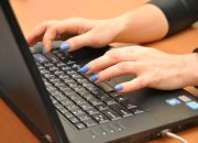 Na zdjęciu widać damskie dłonie na klawiaturze komputera typu laptop.