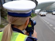 Na zdjęciu widać umundurowaną policjantkę z drogówki, która dokonuje pomiaru prędkości.
