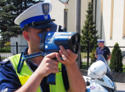 Na zdjęciu jest umundurowany policjant z drogówki, który dokonuje pomiaru prędkości miernikiem prędkości.
