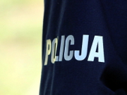 Na zdjęciu widać rękaw policyjnego T-shirtu z odblaskowym napisem Policja.