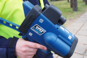 Na zdjęciu widać urządzenie do mierzenia prędkości, które trzyma policjant.