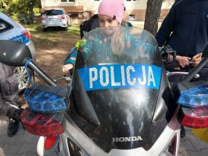 Na zdjęciu jest dziewczynka siedząca na policyjnym motocyklu.