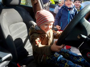 Na zdjęciu widać uśmiechniętego chłopca na siedzeniu kierowcy, który trzyma kierownice pojazdu.