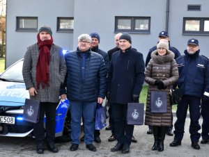 Na zdjęciu widać przedstawicieli samorządów z powiatu otwockiego ustawiony przy oznakowanym radiowozie. Wszyscy są odwróceni przodem do zdjęcia.
