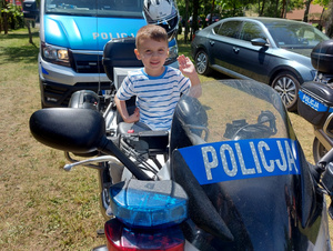 Chłopiec siedzący na policyjnym motocyklu.