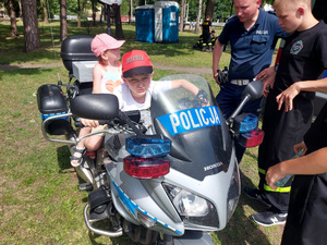 Na zdjęciu jest dwójka dzieci siedzących na policyjnym motocyklu.