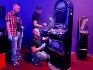 Na zdjęciu widać trzech nieumundurowanych funkcjonariuszy, którzy dokonują oględzin automatu.